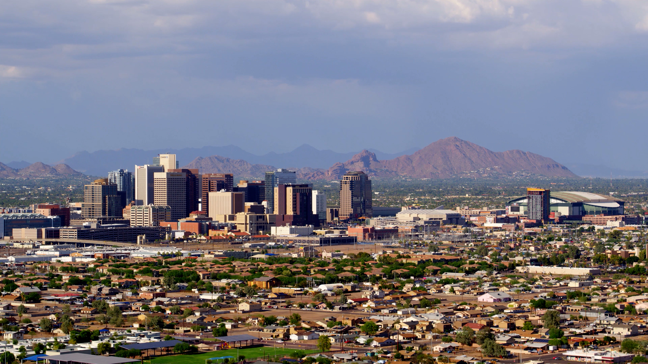owntown Phoenix skyline with Camelback Mountain in the background, viewed over residential neighborhoods